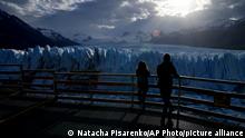 Tourists watch the Perito Moreno Glacier at Los Glaciares National Park, near El Calafate, Argentina, Monday, Nov. 1, 2021. World leaders are gathered in Scotland at a United Nations climate summit, known as COP26, to push nations to ratchet up their efforts to curb climate change. Experts say the amount of energy unleashed by planetary warming could melt much of the planet's ice, raise global sea levels and increase extreme weather events. (AP Photo/Natacha Pisarenko)