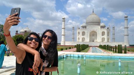 Touristinnen fotografieren sich vorm Taj Mahal in Indien