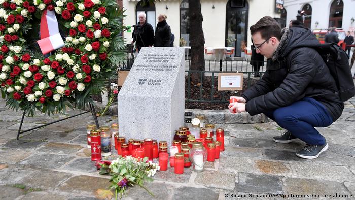 A man lights a candle next to a memorial for the victims of last year's attack in Vienna