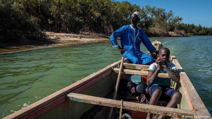 Un hombre y un niño en un bote de madera frente a la costa de Saint Louis, Senegal.