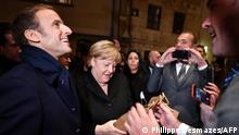 Outgoing German Chancellor Angela Merkel (C) and France's President Emmanuel Macron (L) receive flowers and a bottle of wine as gifts upon their arrival for talks, in Beaune, Eastern France, on November 3, 2021. - I am now leaving this European Union in my responsibility as Chancellor in a situation that worries me, said Merkel on October 22. We have overcome many crises, through respect and efforts to find common solutions, but we have a series of unresolved problems, she warned. Angela Merkel's Christian Democrats (CDU) will pick their next leader through an unprecedented rank-and-file vote after a dismal result in September's election, party chiefs said on November 2. (Photo by PHILIPPE DESMAZES / various sources / AFP)