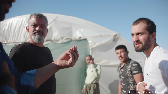 German aid worker Jan Jessen (left) meets with Yazidi men at a refugee camp outside a tent