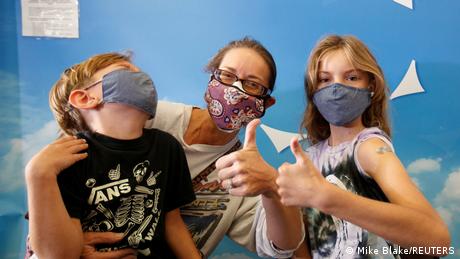 A mother and her kids, giving vaccines the thumbs up