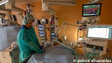 Chefarzt Lorenz Nowak untersucht in Schutzkleidung in einem Intensivbett-Zimmer in der Asklepios Klinik einen geheilten Corona-Patienten, der von der Beatmungsmaschine entwöhnt werden muss.