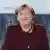 Angela Merkel, wearing a dark purple suit jacket, smiling at the camera