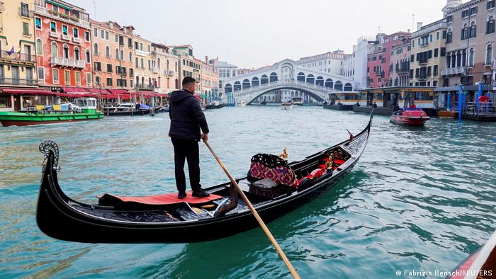 A man rowing a gondola on the canals of Venice.