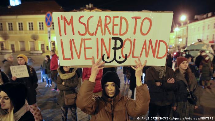 A woman carries a banner that reads, I'm scared to live in Poland.
