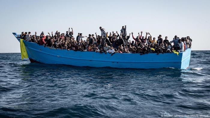Des réfugiés sont assis dans un bateau trop plein sur la Méditerranée 
