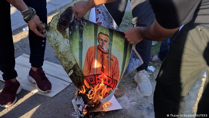 Supporters of Iraqi Shiite armed groups burn portraits of Prime Minister Mustafa al-Kadhemi and Iraq security officials