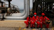 Trabajadores de la industria petrolera hacen una pausa una refinería venezolana.