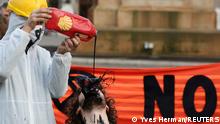 A man pours fake fuel on the face of a protester as they perform at a demonstration against the fossil fuel industry during the UN Climate Change Conference (COP26), in Glasgow, Scotland, Britain, November 7, 2021. REUTERS/Yves Herman