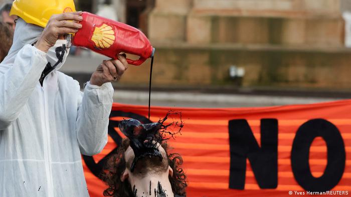 One protester pouring fake oil onto the face of another at a demonstration in Glasgow