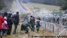 Migrants gather near a barbed wire fence in an attempt to cross the border with Poland in the Grodno region, Belarus November 8, 2021. Leonid Scheglov/BelTA/Handout via REUTERS ATTENTION EDITORS - THIS IMAGE HAS BEEN SUPPLIED BY A THIRD PARTY. NO RESALES. NO ARCHIVE. MANDATORY CREDIT.