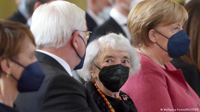 Sobrevivente do Holocausto Margot Friedländer entre presidente alemão, Frank-Walter Steinmeier, e chefe de governo, Angela Merkel