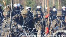A picture taken on November 9, 2021 shows Poland's security personnel behind a barbed wire fence at the Belarusian-Polish border where thousands of migrants gathered aiming to enter EU member Poland. - Poland and Belarus squared off on November 9 over thousands of migrants aiming to enter EU member Poland, with Warsaw saying the wave threatened the security of the entire bloc. Minsk warned against provocations on the border, where armed troops from both countries are deployed amid escalating tensions. Trapped between the rhetoric are thousands of people, many escaping war and poverty in the Middle East, trying to survive outdoors in squalid conditions as temperatures dip toward freezing. - Belarus OUT (Photo by Leonid Shcheglov / BELTA / AFP) / Belarus OUT (Photo by LEONID SHCHEGLOV/BELTA/AFP via Getty Images)