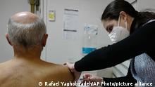 Pharmacist Laetitia Marciano administrates a booster shot of Pfizer COVID-19 vaccine to Pascal Rigaud, 71, Monday, Oct. 25, 2021 in Paris. Worried that the flu and COVID-19 could together trigger a winter-time double-whammy of new infections and deaths, France is forging ahead with a nationwide vaccination program against both diseases, offering simultaneous jabs in both arms to millions of at-risk people. (AP Photo/Rafael Yaghobzadeh)