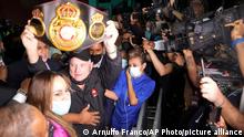 Panama's former President Ricardo Martinelli, center, lifts a boxing tittle belt as talks to reporters outside courthouse after he was found not guilty of political espionage, in Panama City, Tuesday, Nov. 9, 2021. (AP Photo/Arnulfo Franco)