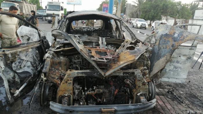 A security man inspects the wreckage of a car at the site of an explosion that killed a journalist in Aden