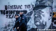 Police officers walk past a mural depicting former Bosnian Serb military chief Ratko Mladic in Belgrade on November 9, 2021. - Police officers have been stationed at the site of the large mural in Belgrade of the convicted war commander, which human rights activists want removed. The gathering was banned by the police to prevent possible conflicts between human rights activists and right-wing nationalists who consider the Serbian general a hero. (Photo by OLIVER BUNIC / AFP)