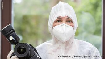 Journalisten in einem Corona-Schutzanzug