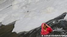 A Hindu woman worships the Sun god as she stands amidst the foam covering the polluted Yamuna river during the Hindu religious festival of Chhath Puja in New Delhi, India, November 10, 2021. REUTERS/Adnan Abidi REFILE - CORRECTING FESTIVAL'S NAME TPX IMAGES OF THE DAY