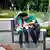 An Iranian couple sits on a wall and fiddles with their mobile phones
