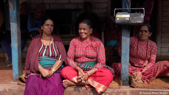 Frauen in bunter traditioneller Kleidung sitzen auf einer Veranda in Nepal