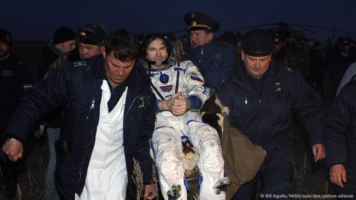 Astronaut Marcos Pontes being carried by men after landing back on Earth