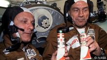 U.S. commander Thomas Stafford and docking module pilot Deke Slayton participate in a toast to a successful docking. The tubes have the labels of famous Russian vodka brands, but actually contained borscht, a beet soup.