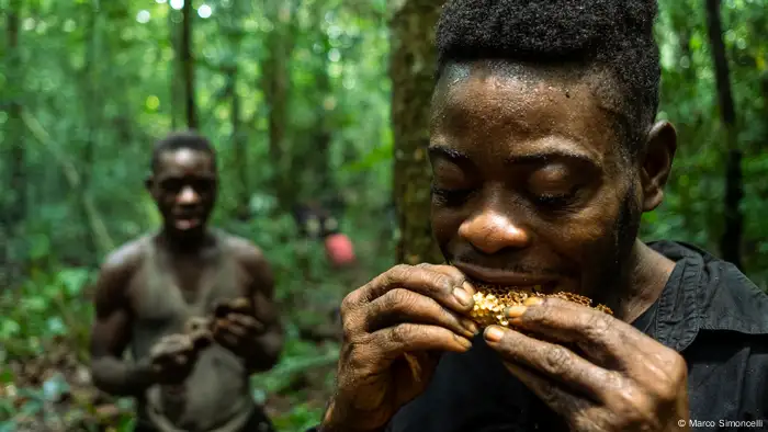 A man sucks on a honeycomb in the forest