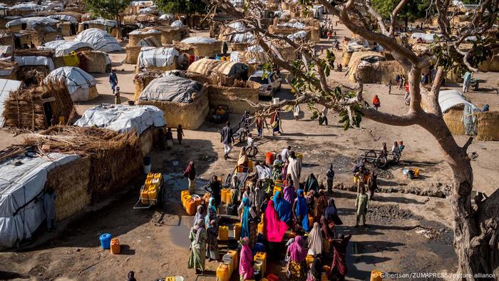 Nigerian refugees wait to fill containers with water at a borehole provided by UNICEF