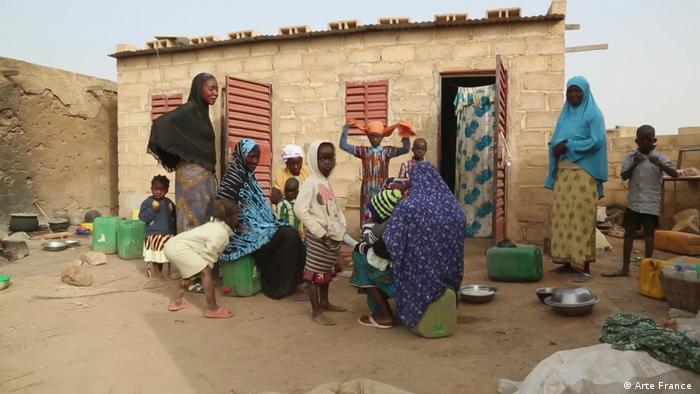 Des femmes et des enfants rassemblés dans la cour d'une maison, dans un village burkinabé