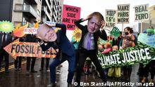Climate activists wear the masks of US President Joe Biden (L) and British Prime Minister Boris Johnson at an anti-fossil fuel protest in Glasgow on November 12, 2021, during the COP26 UN Climate Change Conference. - A draft statement of the COP26 summit Friday called on nations to ease their reliance on fossil fuels as talks entered their final hours without any sign of delivering the emissions cuts needed to limit global warming to 1.5C. (Photo by Ben STANSALL / AFP) (Photo by BEN STANSALL/AFP via Getty Images)
