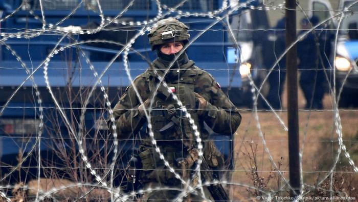 A Polish guard in front of a barbed wire fence