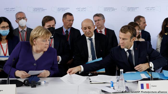 French President Emmanuel Macron, right, and German Chancellor Angela Merkel attend a conference on Libya in Paris Friday