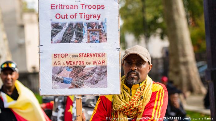 Protester holds placard telling Eritrean troops to stop using starvation as a weapon of war