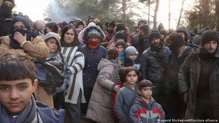 Men, women and children wait at the border between Belarus and Poland