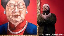 Chinese dissident artist Badiucao poses next to his artwork entitled Carrie Lam, 2018 on November 12, 2021 at the exhibition China is (not) near -- works of a dissident artist, opening at the Santa Giulia museum in Brescia, Lombardy. - Exhibiting a torture instrument as an innocent rocking chair, Chinese dissident artist Badiucao mocks the propaganda of Beijing in a new show, while appropriating its codes. (Photo by Piero CRUCIATTI / AFP) / RESTRICTED TO EDITORIAL USE - MANDATORY MENTION OF THE ARTIST UPON PUBLICATION - TO ILLUSTRATE THE EVENT AS SPECIFIED IN THE CAPTION