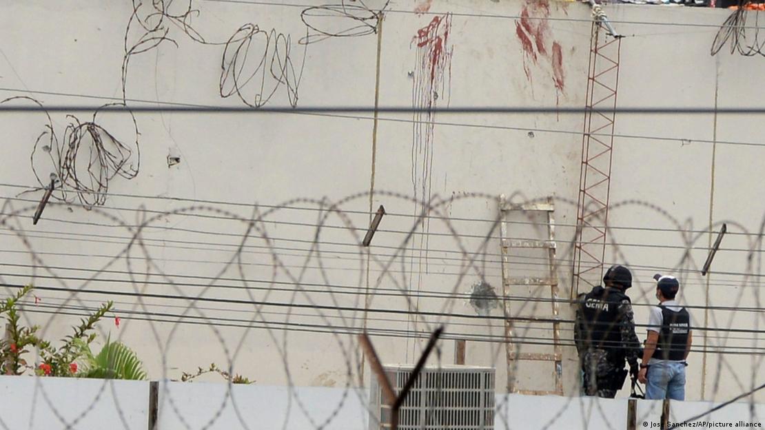 Dois policiais observam marcas de sangue em uma parede externa de uma penitenciária no Equador