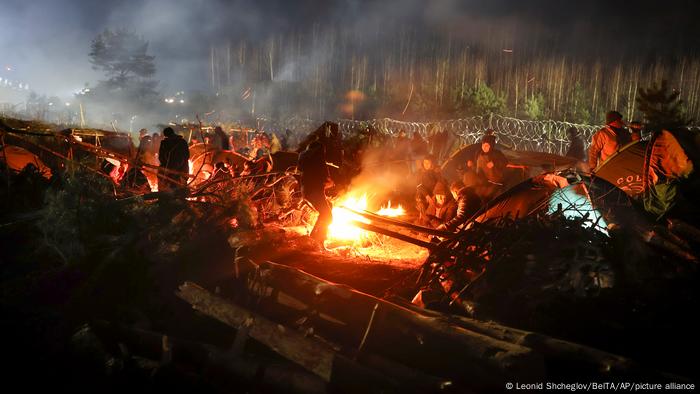 Migrants huddle around a fire at a makeshift camp in freezing conditions on the Belarusian border