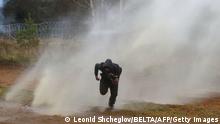 TOPSHOT - A man runs away from a water cannon used by Polish law enforcement officers against migrants attempting to break into Poland at the Bruzgi-Kuznica border crossing on the Belarusian-Polish border on November 16, 2021. - - Belarus OUT (Photo by Leonid SHCHEGLOV / BELTA / AFP) / Belarus OUT (Photo by LEONID SHCHEGLOV/BELTA/AFP via Getty Images)