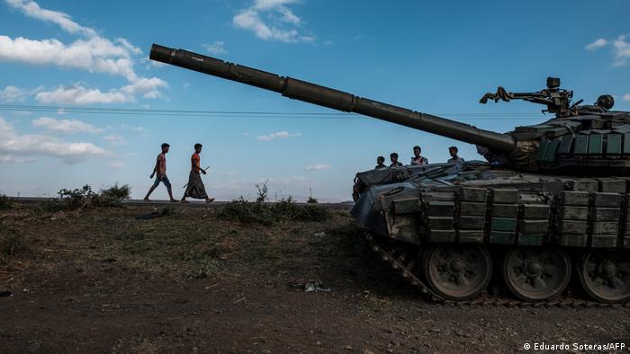 Youngsters walk next to an abandoned tank belonging to Tigrayan forces.