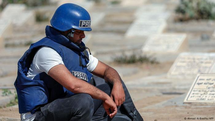 A journalist mourns by the grave of TV reporter Adib al-Janani, who was killed in an attack on Aden airport