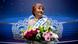 An old woman stands with flowers in front of a tiara An old woman stands with flowers in front of a tiara