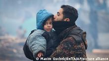 A man kisses a child at the checkpoint Kuznitsa at the Belarus-Poland border near Grodno, Belarus, on Wednesday, Nov. 17, 2021. A Polish government official says migrants camped on the Belarusian side of Poland's eastern border are being taken away by bus, in a sign a tense standoff could be easing. Poland's Border Guard posted on Twitter a video showing migrants with bags and backpacks being directed by Belarus forces away from the border. (Maxim Guchek/BelTA via AP)