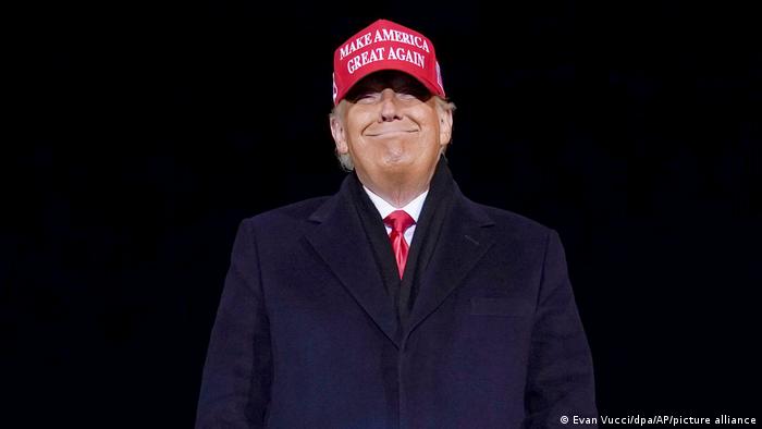 Ex-US President Donald Trump grins widely with a 'Make America Great Again' hat on