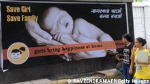 Young Indian women walk past a billboard in New Delhi on July 9, 2010, encouraging the birth of girls. Mostly as a result of sex-selective abortion, India is one of the few countries worldwide with an adverse child sex ratio in favour of boys. Under Indian law, tests to find out the gender of an unborn baby are illegal if not done for medical reasons, but the practice continues in what activists say is a flourishing multi-million-dollar business. Girls in India are often considered a liability, as parents have to put away large sums of money for dowries at the time of their marriage. AFP PHOTO/RAVEENDRAN (Photo credit should read RAVEENDRAN/AFP via Getty Images)