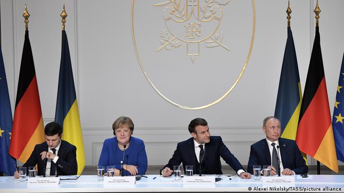 Ukrainian President Volodymyr Zelenskyy, former German Chancellor Angela Merkel, French president Emmanuel Macron and Russian president Vladimir Putin sit at a table in the Elysee Palace, Paris