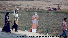 People walk past a cutout of Indian Prime Minister Narendra Modi as they arrive to watch the inauguration of the 341 kilometers (211 miles) long Purvanchal expressway, in Sultanpur district, in the Indian state of Uttar Pradesh, Tuesday, Nov. 16, 2021. (AP Photo/Rajesh Kumar Singh)