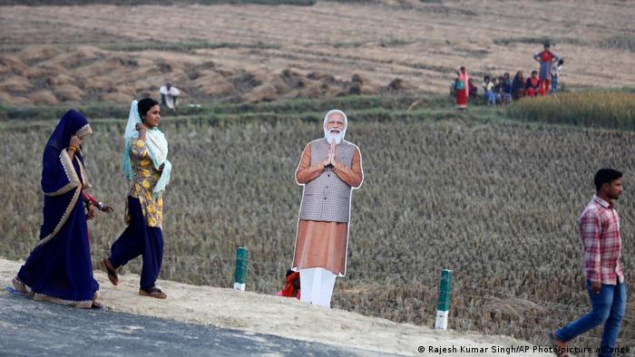 People walk past a cutout of PM Modi in the state of Uttar Pradesh. 